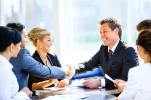 mature businessman shaking hands to seal a deal with his partner and colleagues in a modern office
