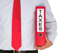 A picture of a businessman holding a binder labeled "taxes."