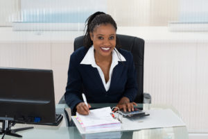 Smiling businesswoman calculating bills at office desk