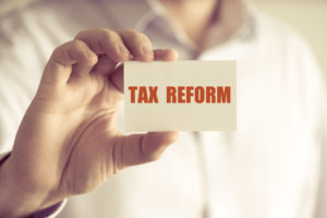 Closeup on businessman holding a card with text tax reform