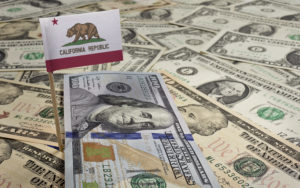 Flag of California sticking in a variety of American dollars.