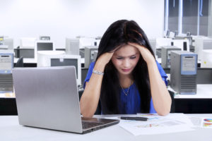 Portrait of stressful businesswoman with laptop and a business chart on paper at office