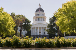 Backlit morning scene of the front of the California State Capitol building in the capital of Sacramento with roses framing the scene