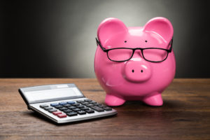 Pink Piggybank With Calculator On Wooden Table