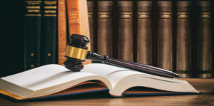 Law gavel on an open book, wooden desk, law books background